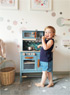 Mädchen mit blauer Kinderküche aus Holz